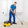 Thumb 44713298 happy male janitor cleaning carpet with vacuum cleaner