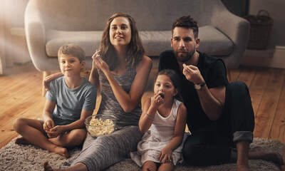 Page medium family sitting on floor watching tv